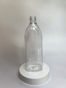 Transparent square plastic container with curved shoulders for airless bottle packaging, displayed on a white platform.